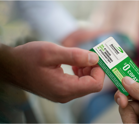 White female in a yellow sweater standing in a pharmacy, not actual Serostim® patient